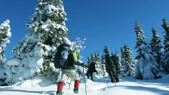man trekking up a snowy mountain in deep snow