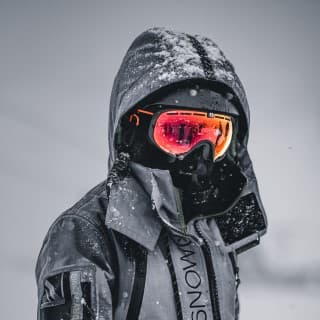 Man wearing white jacket, black full head ski helmet on a snowy day